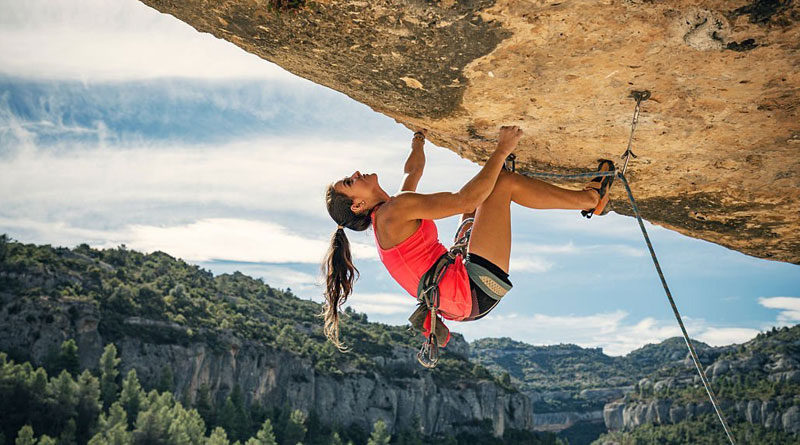 A Female Climber Climbing a Rock with a Harness